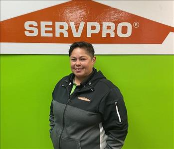 woman standing in front of green wall with SERVPRO logo on it.